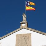 Statue and flags on top of the church at Galilea Majorca
