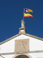 Statue and flags on top of the church at Galilea Majorca